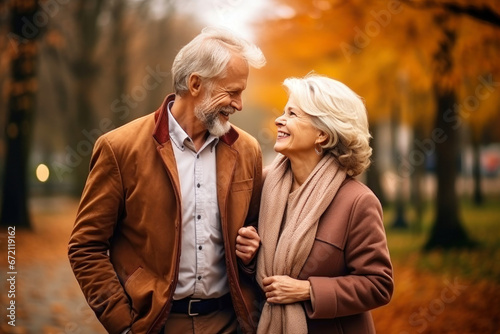 An elderly couple, a man and a woman, hugging in an autumn park. They look at each other with a loving gaze. Old people on a walk. Relationships in old age. Love and romance.