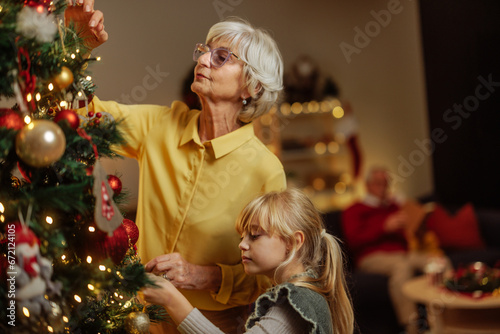 Grandma decorating Christmas tree with her granddaughter
