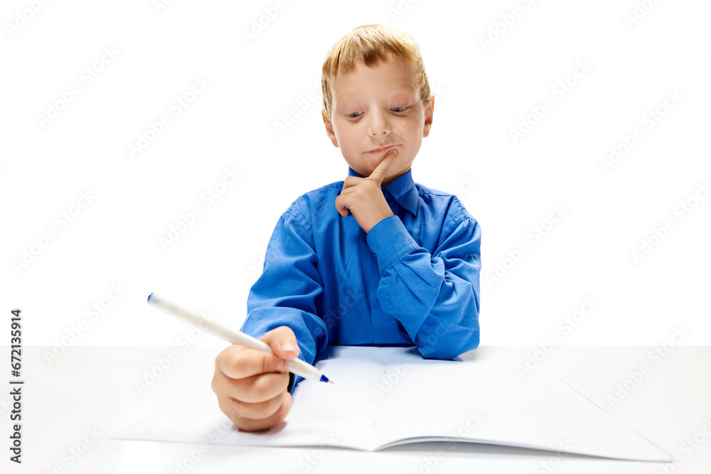 Little boy of elementary class doing homework in copybook. Child study and learn for preschool. Online education. Concept of childhood, International Knowledge Day, study. Copy space for ad. Little boy of elementary class doing homework in copybook. Child study and learn for preschool. Online education. Concept of childhood, International Knowledge Day, study. Copy space for ad.