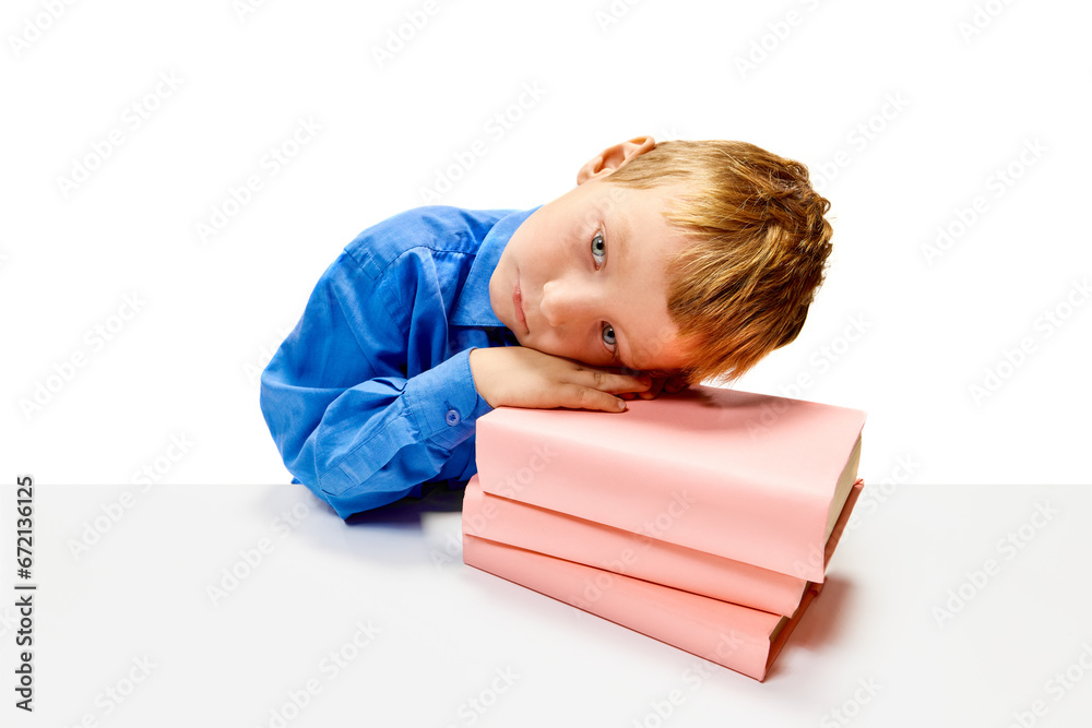 Boring boy of elementary class sitting at desk put his head on textbooks. Child study and learn for preschool. Online education. Concept of childhood, International Knowledge Day. Copy space. ad Boring boy of elementary class sitting at desk put his head on textbooks. Child study and learn for preschool. Online education. Concept of childhood, International Knowledge Day. Copy space. ad