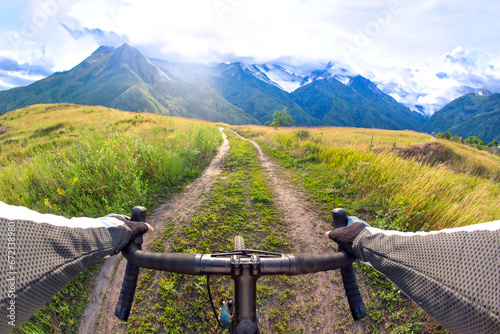 Obraz na płótnie hands on the handlebars of a bicycle of a cyclist riding along a trail in nature
