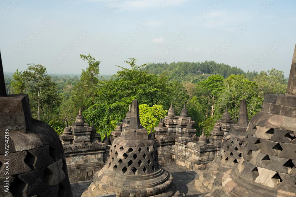 (Selective focus) Stunning view of the Borobudur bell shaped stupas during a beautiful sunrise. Borobudur is a Mahayana Buddhist temple in Magelang Regency in Central Java, Indonesia.