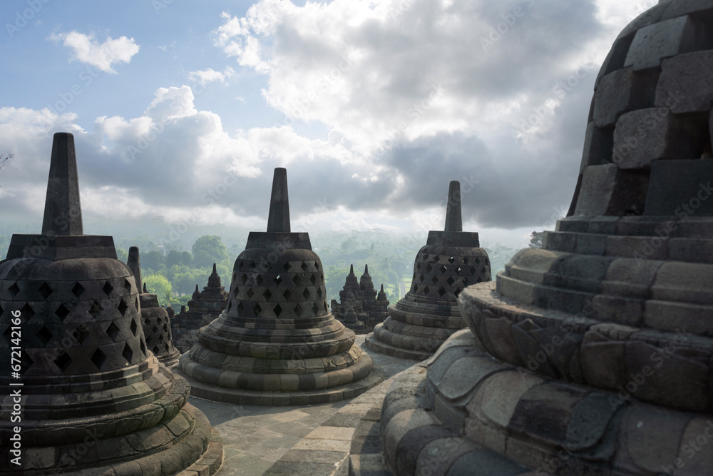 (Selective focus) Stunning view of the Borobudur bell shaped stupas during a beautiful sunrise. Borobudur is a Mahayana Buddhist temple in Magelang Regency in Central Java, Indonesia.