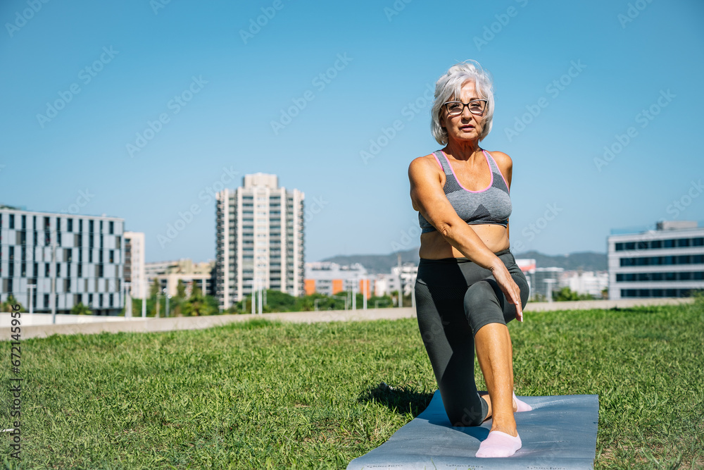 Sportive old woman stretching and doing yoga outdoors