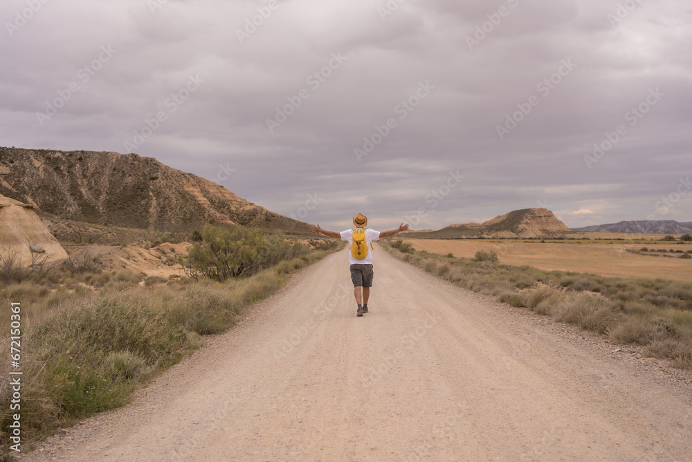 Man gesturing freedom while walking along a sandy footpath