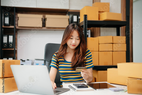 Young woman prepare parcel box and standing check online orders for deliver to customer on tablet, laptop Shopping Online concept.