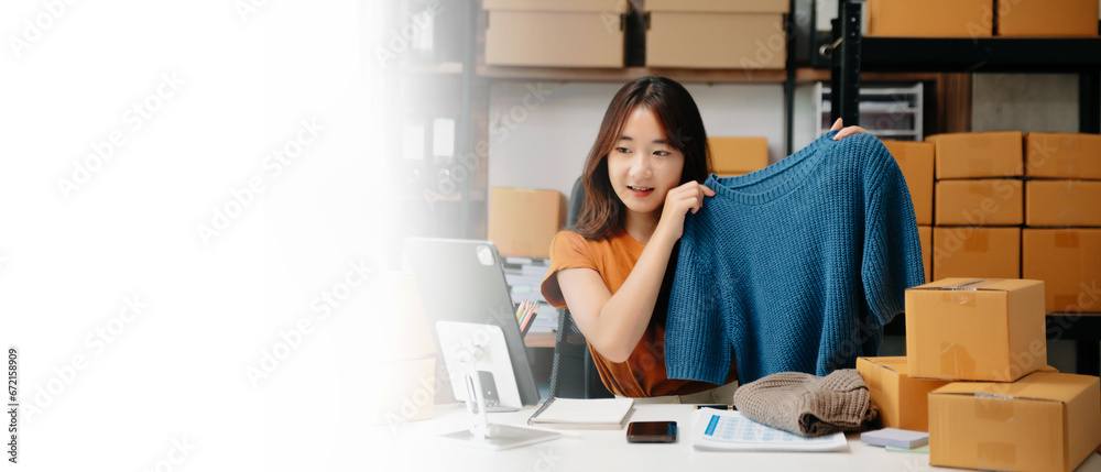 Asian lady blogger showing clothes in front of the camera to recording vlog video live streaming at her shop. Online Shopping Cart notion... Asian lady blogger showing clothes in front of the camera to recording vlog video live streaming at her shop. Online Shopping Cart notion...