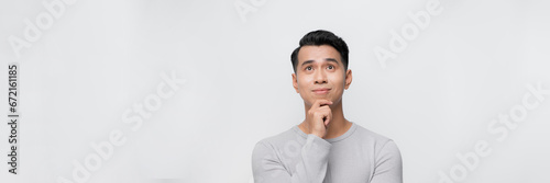 Smart handsome smiling young Asian man thinking with hand on chin on white background. Banner