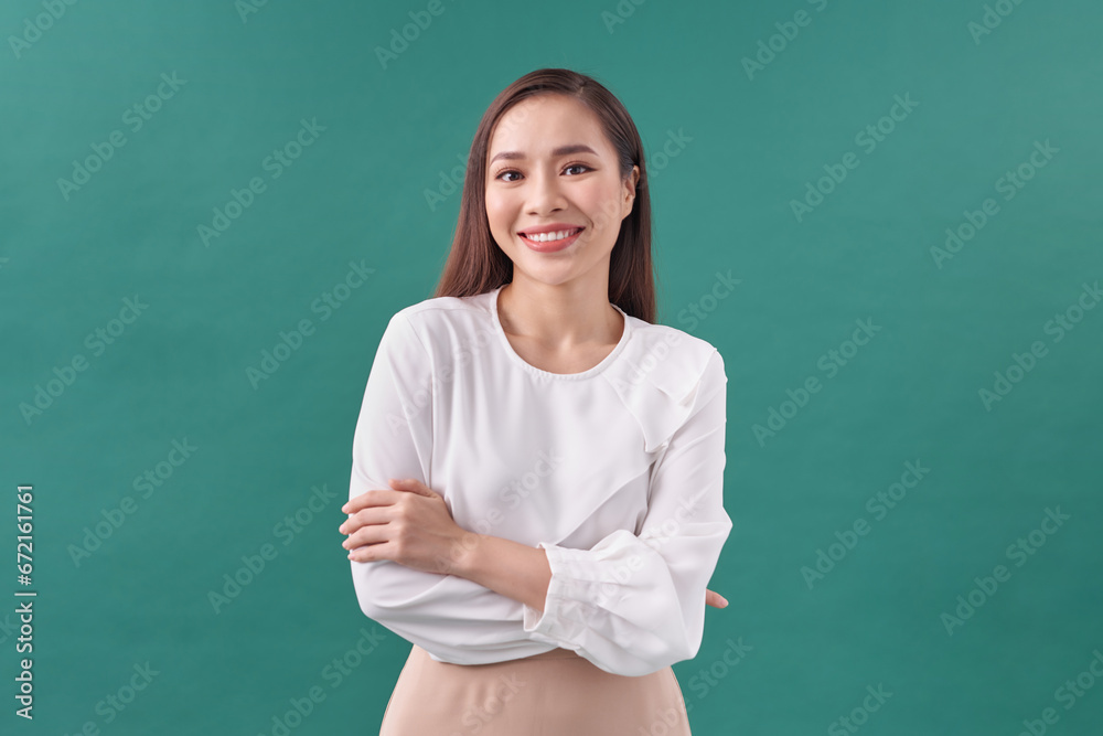 Beautiful girl with folded arms looking at camera against green wall.