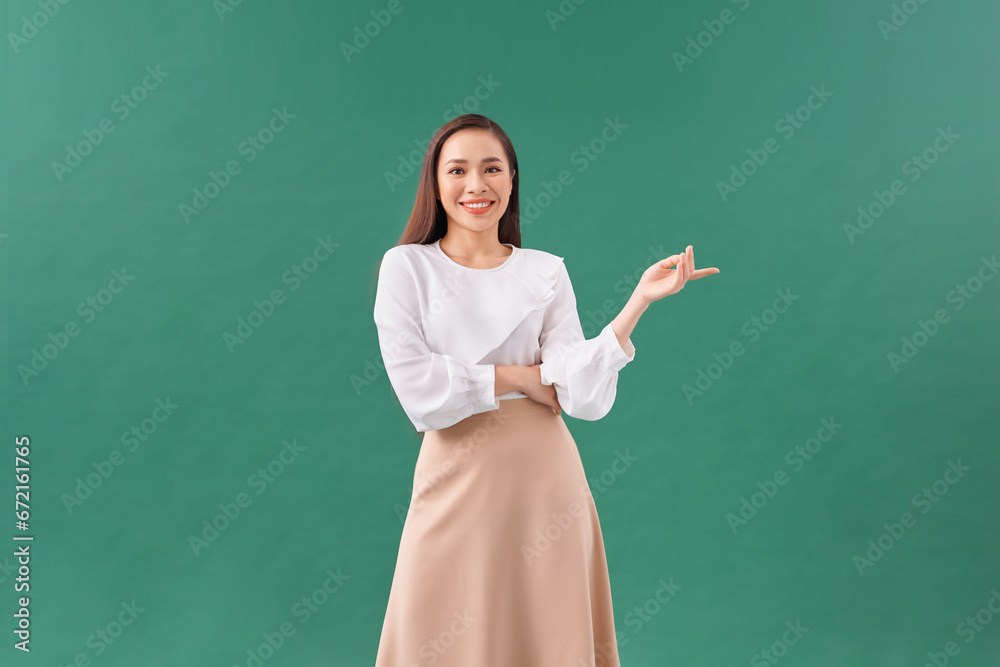 smiling beautiful young woman showing copyspace over green background