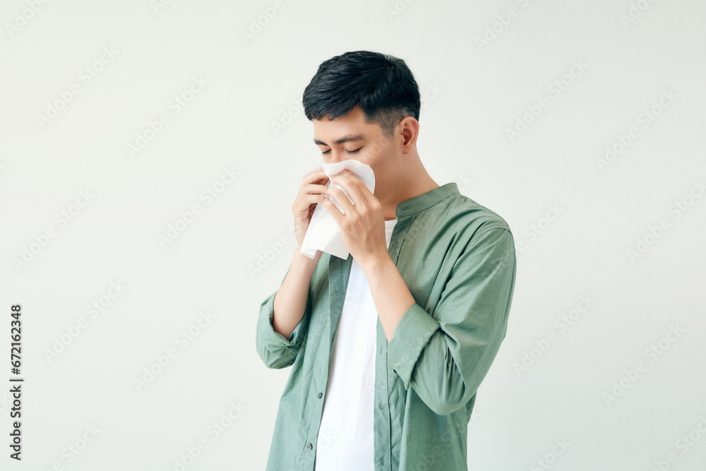 Young man wiping his nose with a tissue on white background Young man wiping his nose with a tissue on white background