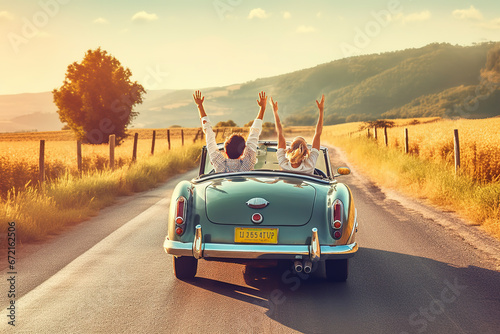 Couple on vacation on the roadtrip having fun driving a convertible car raising the arms to the sky.