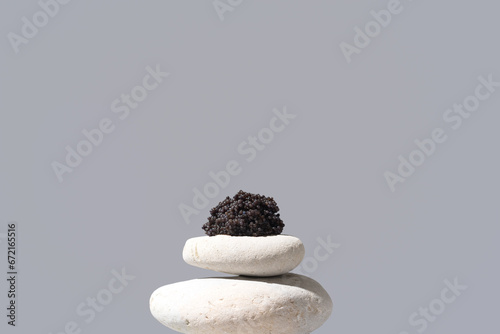 Caviar de esturión sobre piedras blancas. Comida gourmet sobre fondo gris
