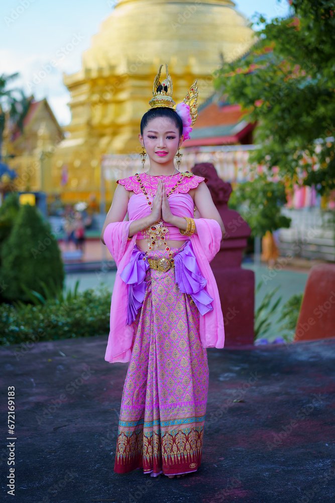 Pretty Asian women wearing beautiful Thai traditional dress in Hundred Thousand Lantern Festival or Yi Peng Festival for worship at Phra That Hariphunchai temple in Lamphun, Thailand.