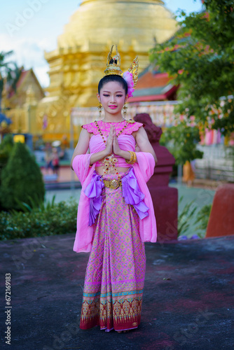 Pretty Asian women wearing beautiful Thai traditional dress in Hundred Thousand Lantern Festival or Yi Peng Festival for worship at Phra That Hariphunchai temple in Lamphun, Thailand.
