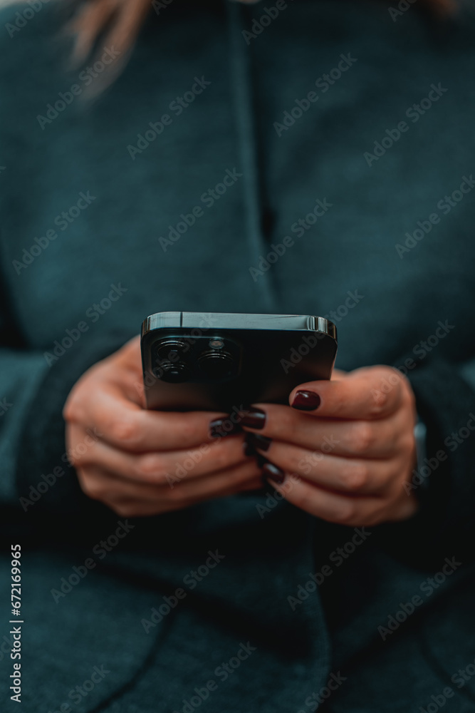 City lifestyle stylish using a phone texting on smartphone app in a street. Young woman with smartphone in hand close-up. City lifestyle stylish using a phone texting on smartphone app in a street. Young woman with smartphone in hand close-up.