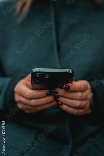 City lifestyle stylish using a phone texting on smartphone app in a street. Young woman with smartphone in hand close-up.