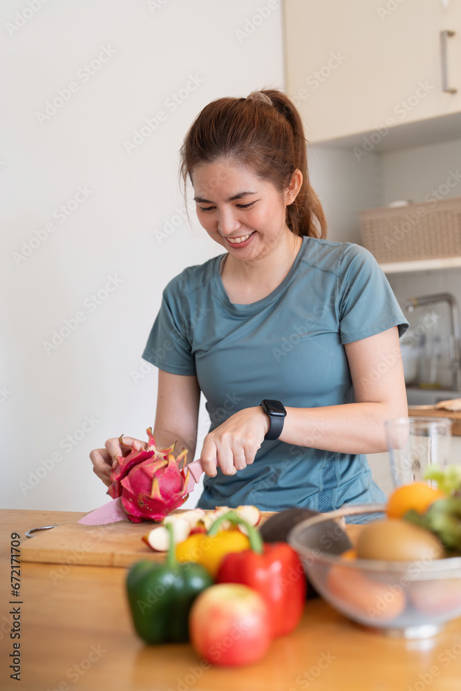 Woman asian cutting fruits and vegetable to prepare a smoothie in the kitchen at home