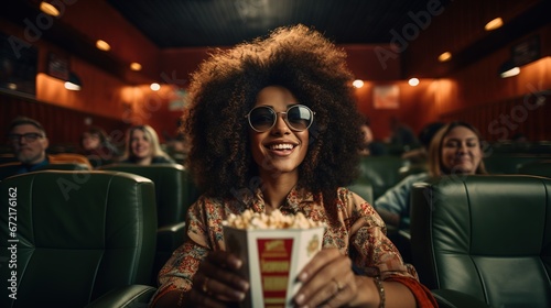 A woman with a happy look is watching a movie in the cinema while holding popcorn. Ai generative © Ewa