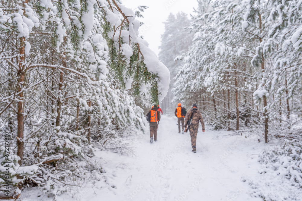 In winter, hunters walk through the forest. 