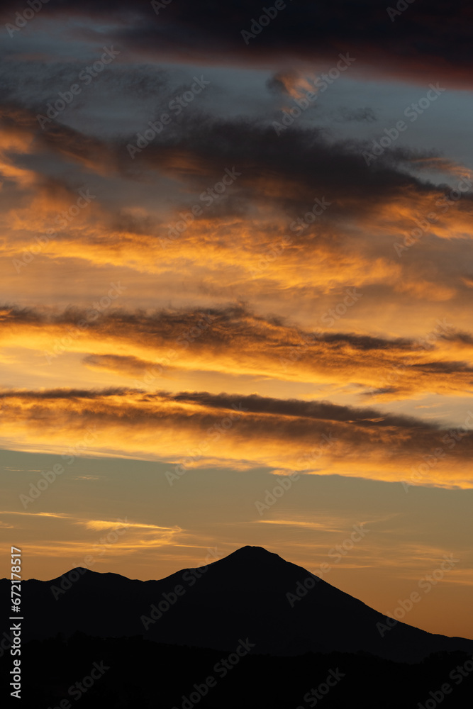 Stunning sunrise with beautiful shades of orange, pink, purple and blue colors with the silhouette of a mountain range. Wallpaper, natural background with copy space.