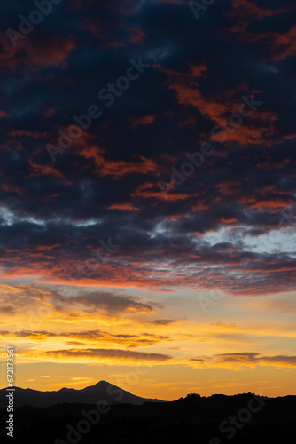 Obraz na płótnie Stunning sunrise with beautiful shades of orange, pink, purple and blue colors with the silhouette of a mountain range. Wallpaper, natural background with copy space. w salonie