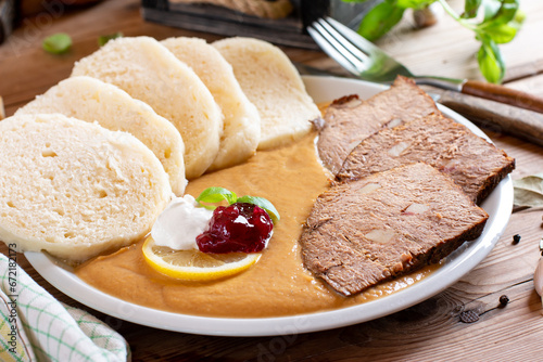 Svickova - Traditional czech dish: Marinated beef sirloin with creamy root vegetable sauce and bread dumplings, topped with cranberries on the table