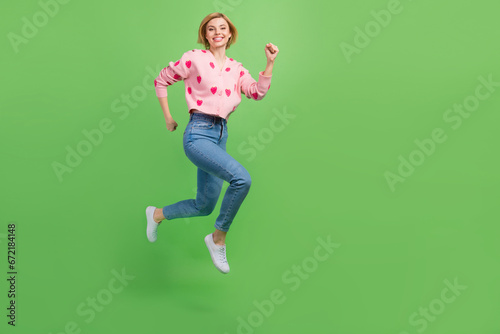 Full body photo of pretty young girl running rush speed dressed stylish pink strawberry print outfit isolated on green color background