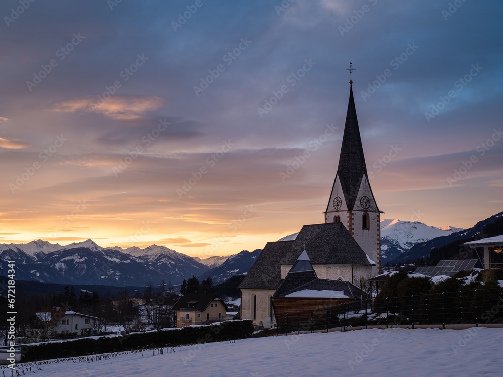 Village church in the mountains, winter christmas landscape, snow mountains, sunset, colorful sky
