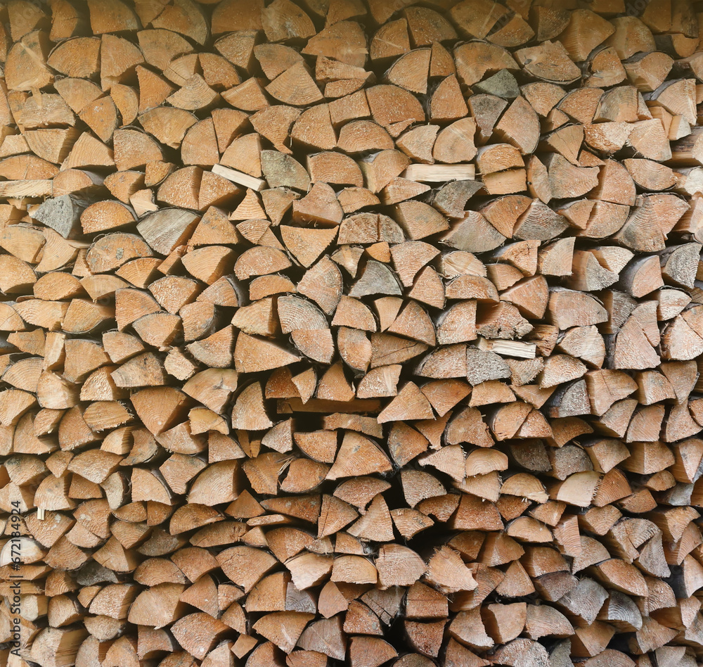 Firewood stacked near the wooden wall of old hut. Many chopped logs of firewood close up Firewood stacked near the wooden wall of old hut. Many chopped logs of firewood close up