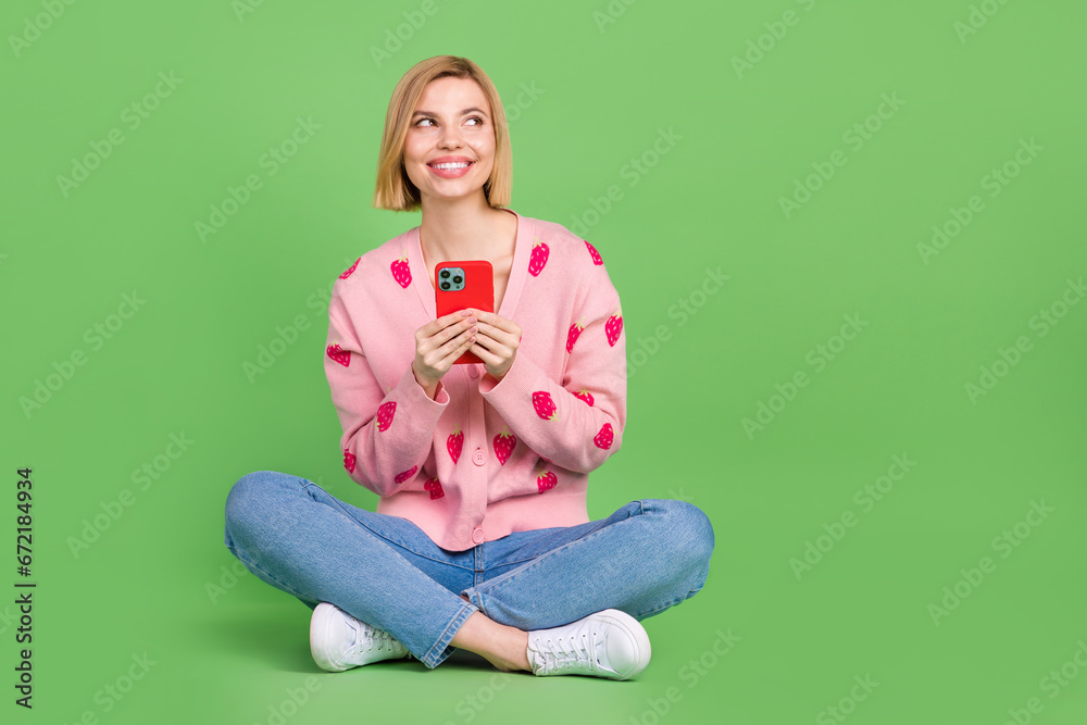 Full body photo of pretty young girl gadget empty space dressed stylish pink strawberry print outfit isolated on green color background Full body photo of pretty young girl gadget empty space dressed stylish pink strawberry print outfit isolated on green color background