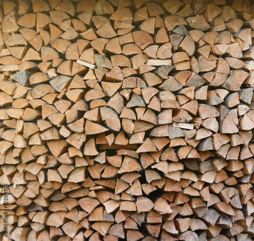 Firewood stacked near the wooden wall of old hut. Many chopped logs of firewood close up