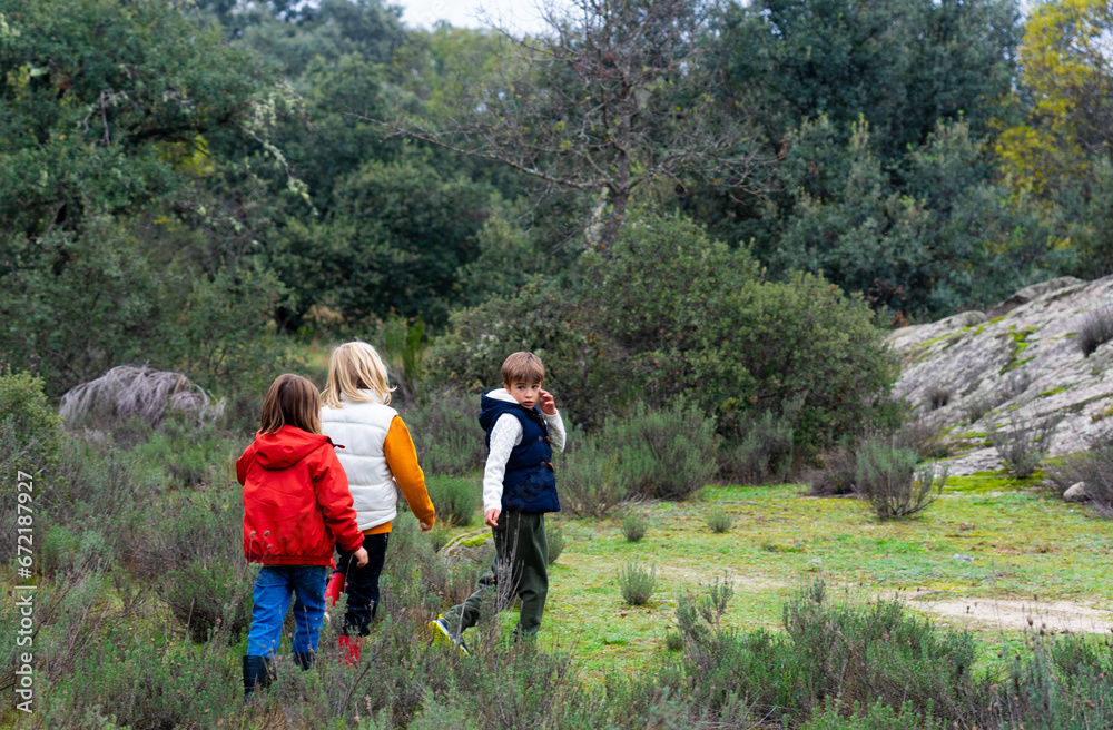 Three children walking through the field seen from behind