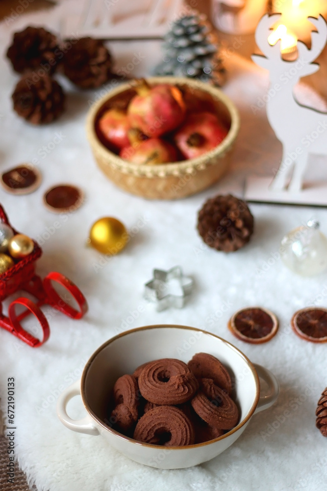 Cup of tea or coffee, glass of wine or juice, bowl of cookies, organic pomegranate, fluffy blanket, pine cones, various Christmas decorations and lit candles on the table. Christmas hygge concept. Cup of tea or coffee, glass of wine or juice, bowl of cookies, organic pomegranate, fluffy blanket, pine cones, various Christmas decorations and lit candles on the table. Christmas hygge concept.