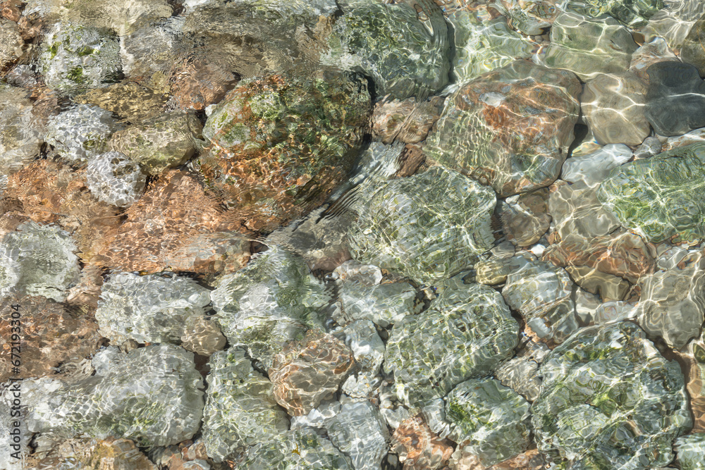 Clear sea water and stones on the rocky Mediterranean coast abstract background
