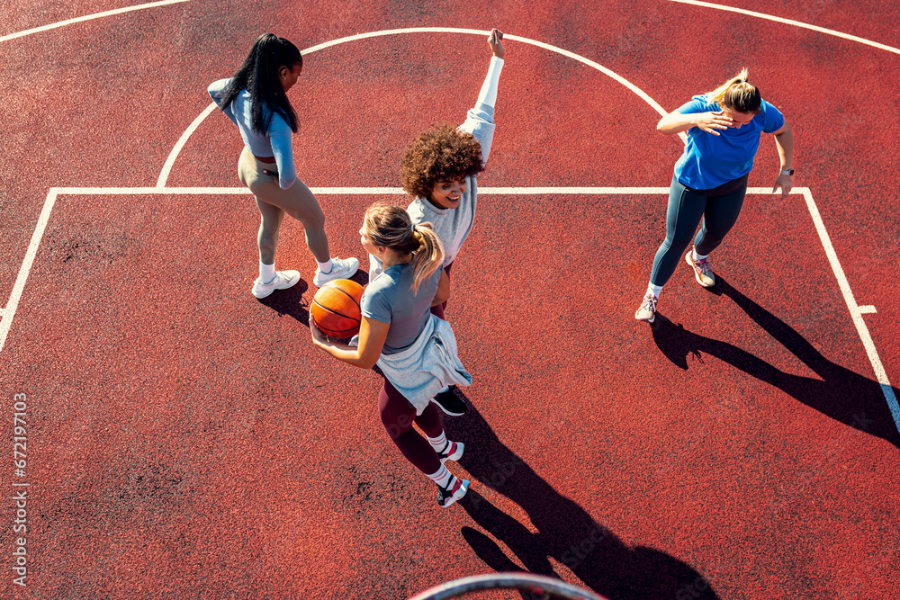 Fototapeta premium Diverse group of young woman having fun playing basketball outdoors, celebrate after scoring.