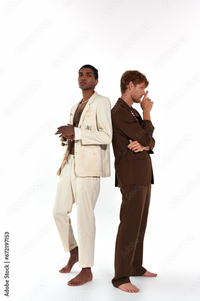 vertical shot of multicultural young male models in elegant suits posing back to back, men power vertical shot of multicultural young male models in elegant suits posing back to back, men power