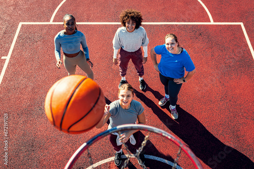 Portait of diverse group of young woman having fun playing basketball outdoors.