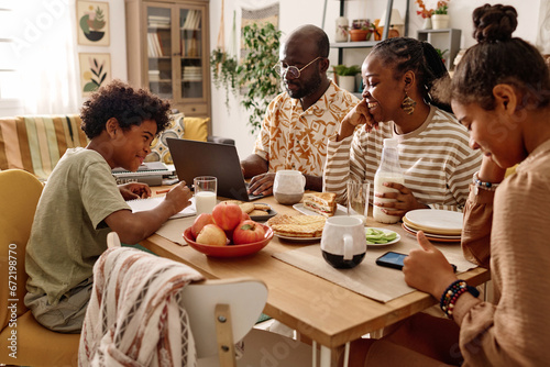 Cheerful Black family having breakfast at big table