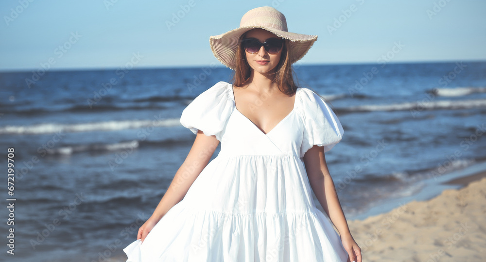 Happy smiling blonde woman is posing on the ocean beach with sunglasses and a hat Happy smiling blonde woman is posing on the ocean beach with sunglasses and a hat