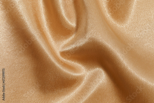 texture of crumpled wrinkled shiny beige synthetic or polyester fabric close-up. Fabric for sewing clothes. background for your mockup
