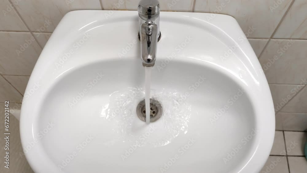 Man opens the faucet in the bathroom Man opens the faucet in the bathroom