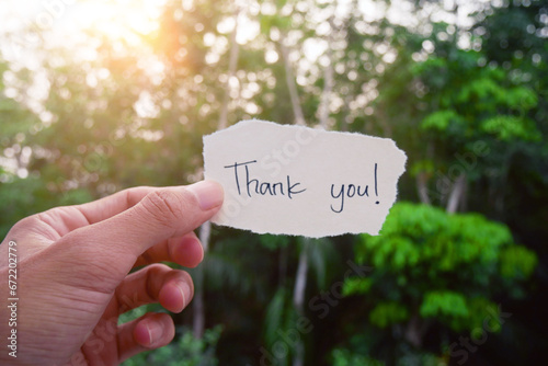 Hand-holding paper with the words 'Thank you!' handwritten on a torn piece.