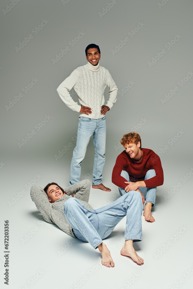vertical shot of diverse cheerful friends in vibrant sweaters posing on gray backdrop, men power vertical shot of diverse cheerful friends in vibrant sweaters posing on gray backdrop, men power