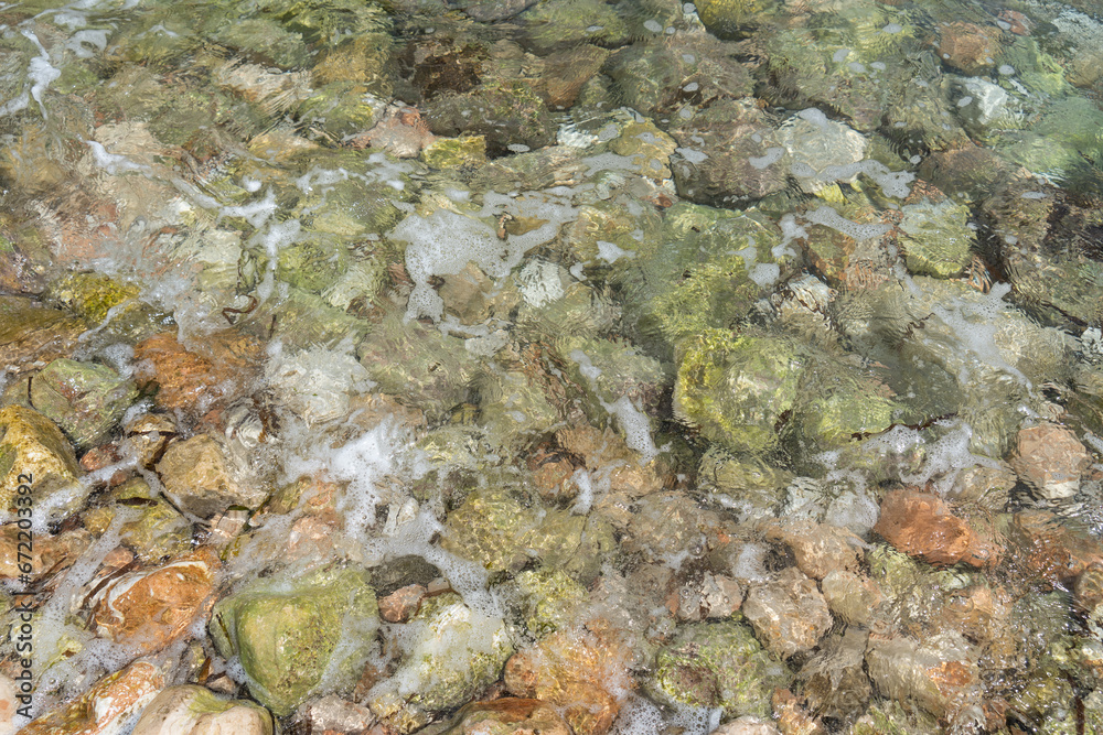 Flowing sea water and rocks on the Mediterranean coast abstract rocky beach background