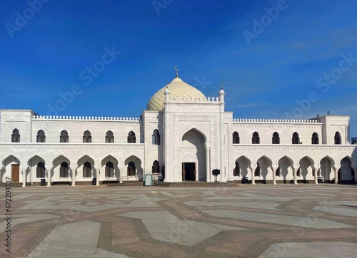 Square,white palace with dome and crescent, blue sky.