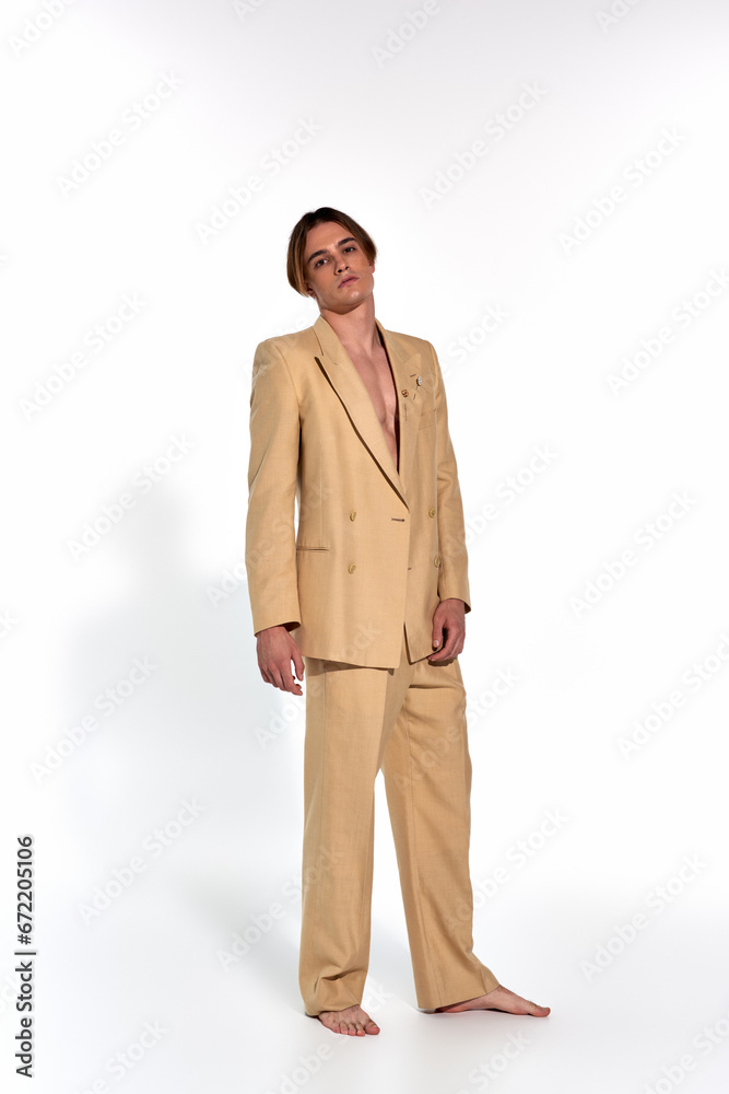 vertical shot of appealing sexy man in beige elegant suit standing and looking at camera, fashion vertical shot of appealing sexy man in beige elegant suit standing and looking at camera, fashion