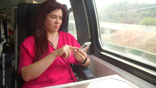 Travel concept by public transport. Woman using smartphone app taking pictures of the view while traveling in train photo