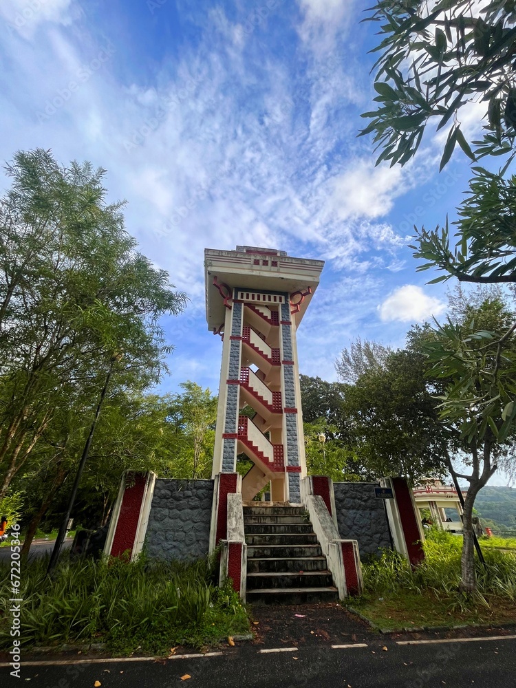 A watch tower with crisscross stairs under blue sky