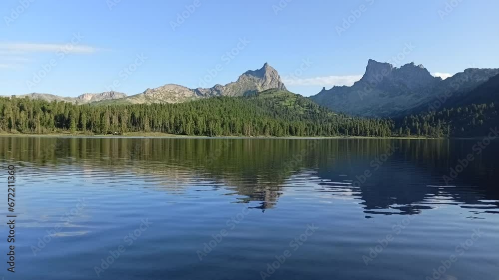 Small ripples on the surface of a large lake surrounded by high peaked mountains on a sunny summer evening. Lake Svetloe, Ergaki Nature Park, Krasnoyarsk Territory, Siberia, Russia. Small ripples on the surface of a large lake surrounded by high peaked mountains on a sunny summer evening. Lake Svetloe, Ergaki Nature Park, Krasnoyarsk Territory, Siberia, Russia.